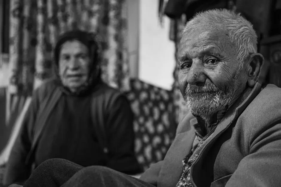 Dos personas mayores en retrato blanco y negro: hombre con barba blanca en primer plano